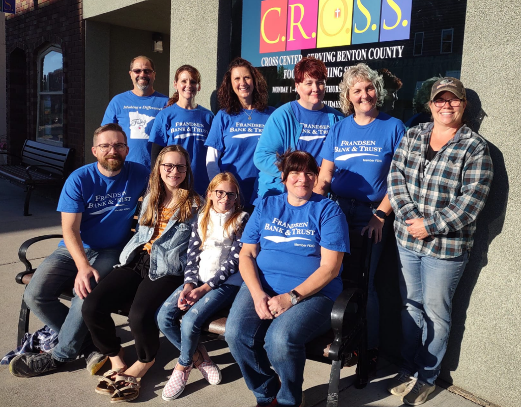 Current image: People in blue shirts stand together outside a building with a sign that says C.R.O.S.S.