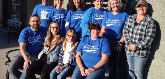 People in blue shirts stand together outside a building with a sign that says C.R.O.S.S.