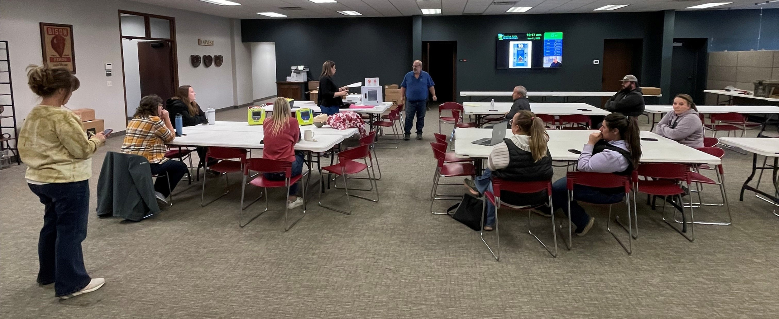 Centra Sota team members from multiple locations sit at tables in large room for training on AEDs