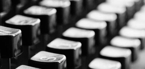 Black and white close-up of vintage typewriter keys, softly focused with shallow depth of field.