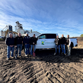 Seven people stand before a Central Sota truck at a construction site on a clear, sunny day.