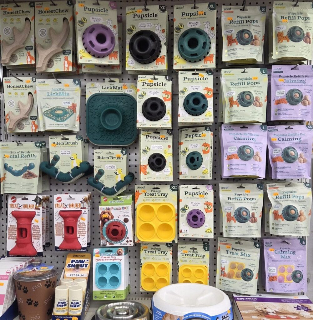 Dog treat toys, chews, trays, and refill packs neatly arranged on a pet store shelf.