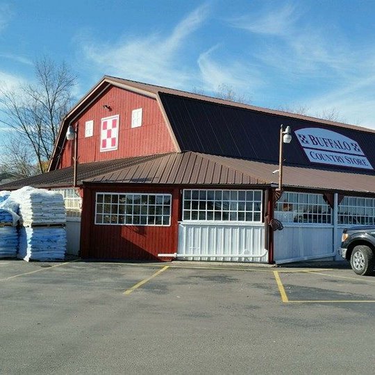 Buffalo Country Store in a red barn-style building, stacked bags by the entrance in a parking lot.