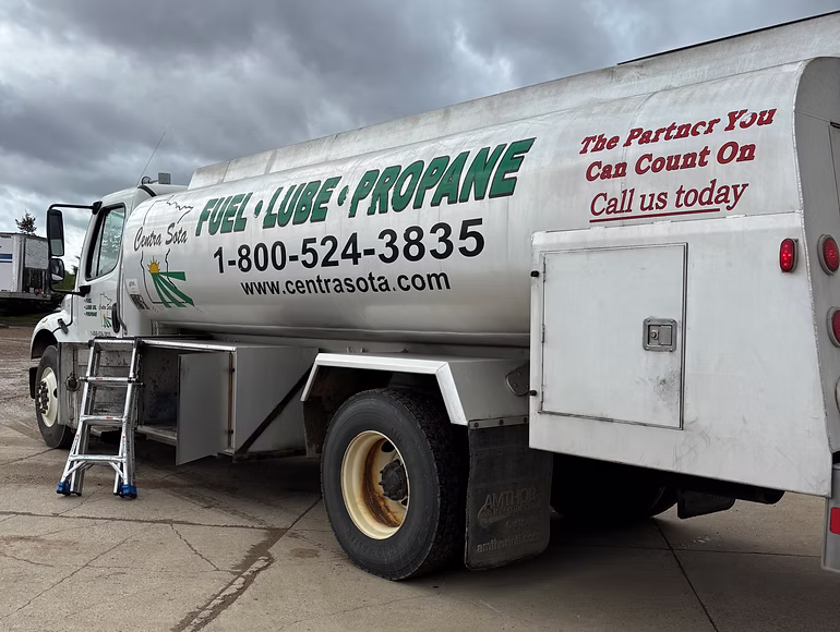White fuel truck displaying "Fuel • Lube • Propane" and contact numbers along its side.