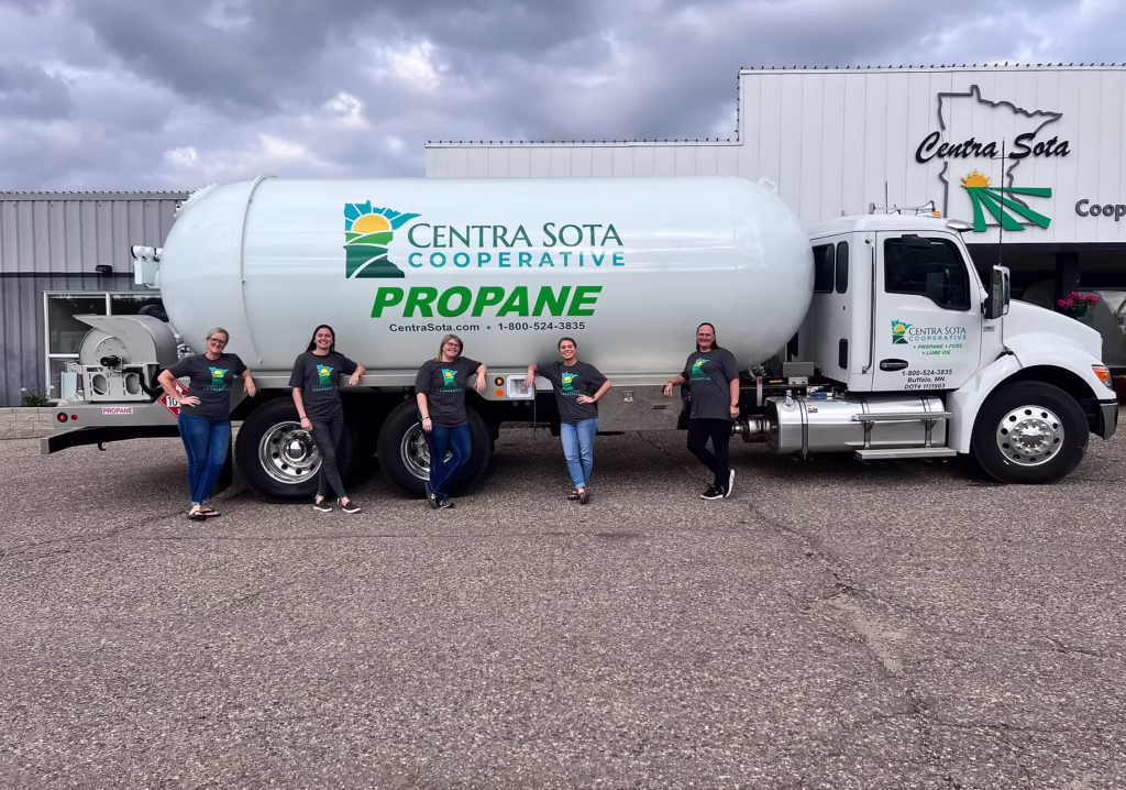 Five people pose together in front of a Centra Sota Cooperative propane truck parked near a building.